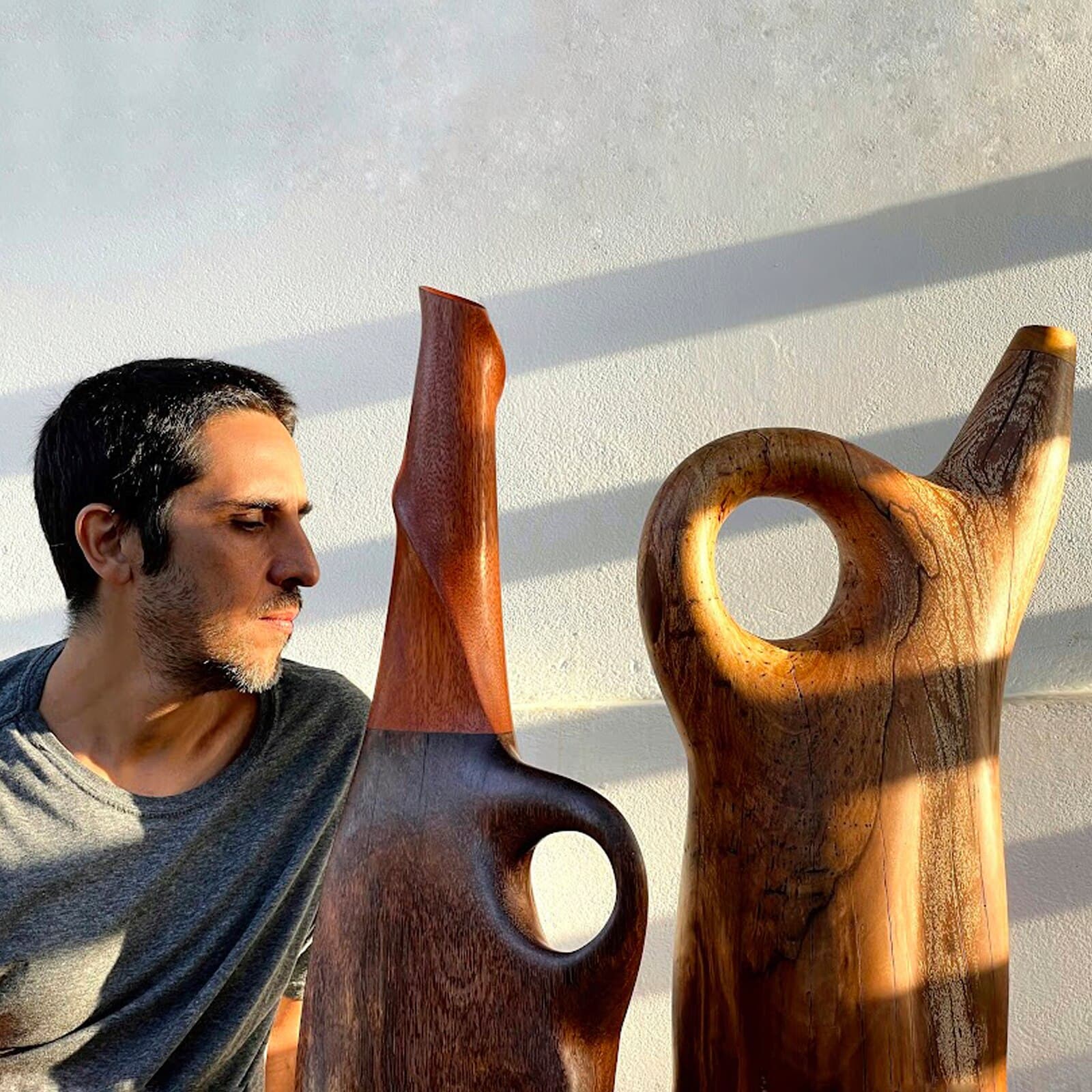 Fred Gontijo, artesão, ao lado de duas peças esculpidas em madeira